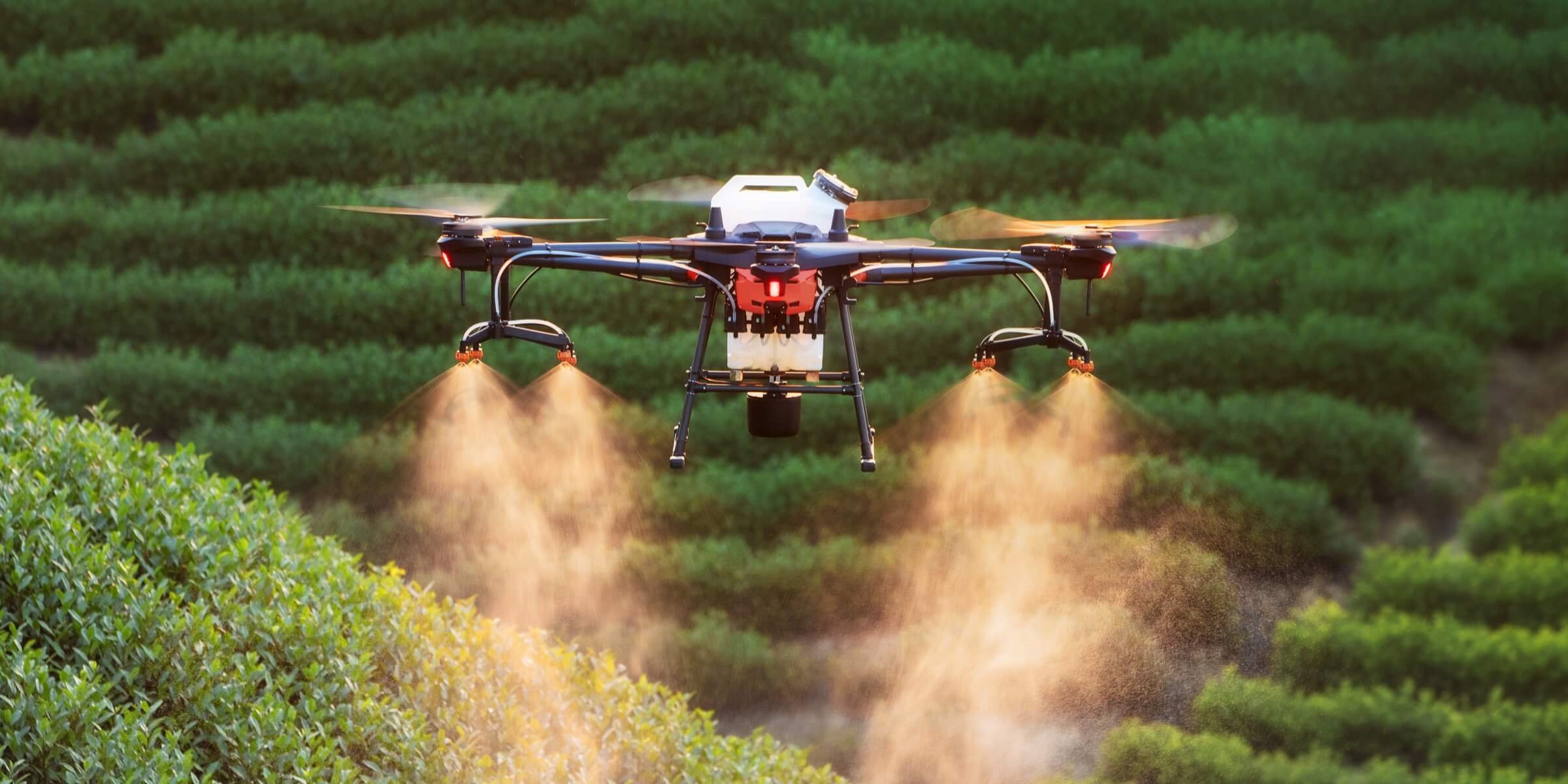 Drone spraying crops over farmland